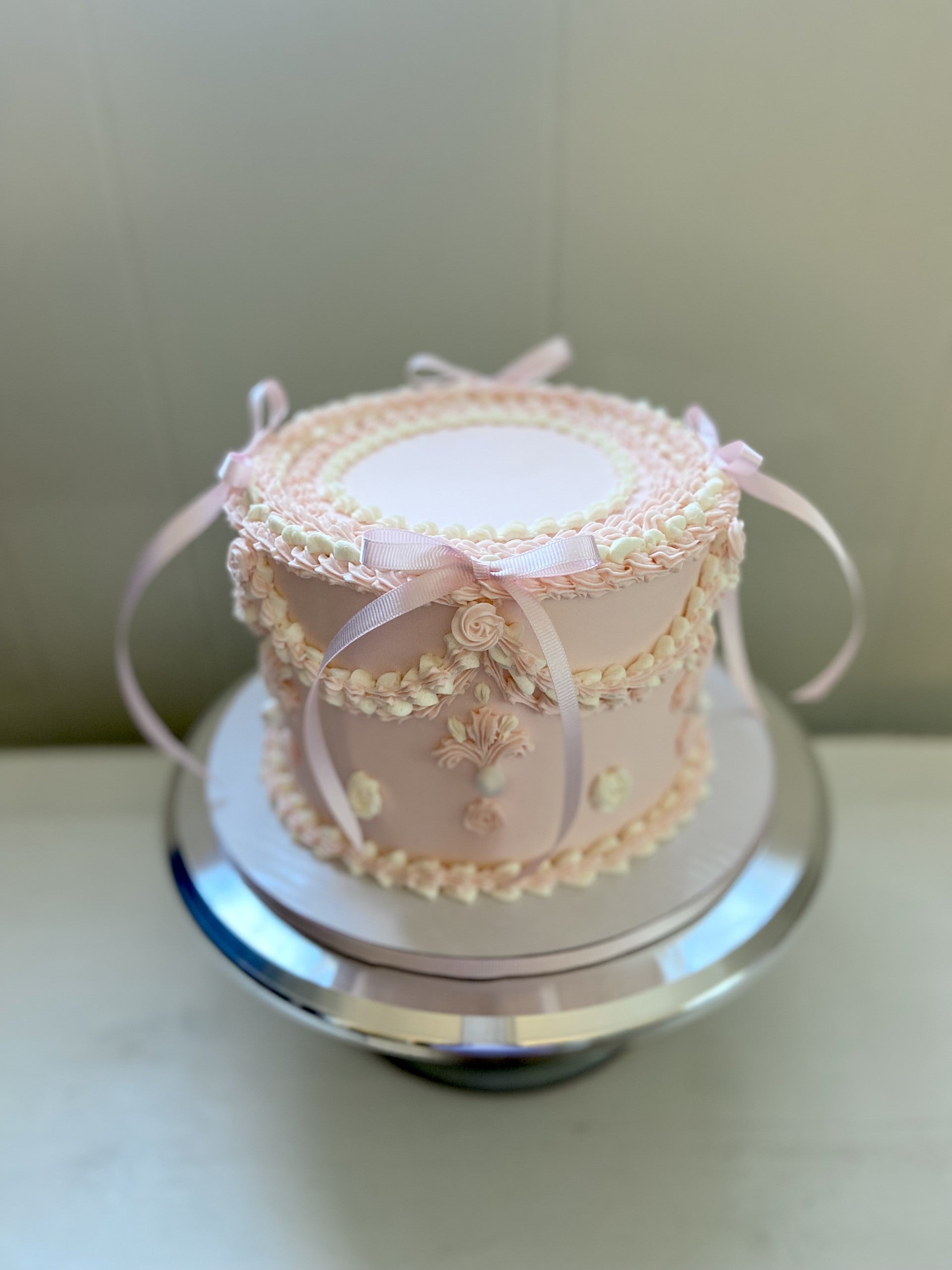 Pink cake with vintage piping and pink bows.