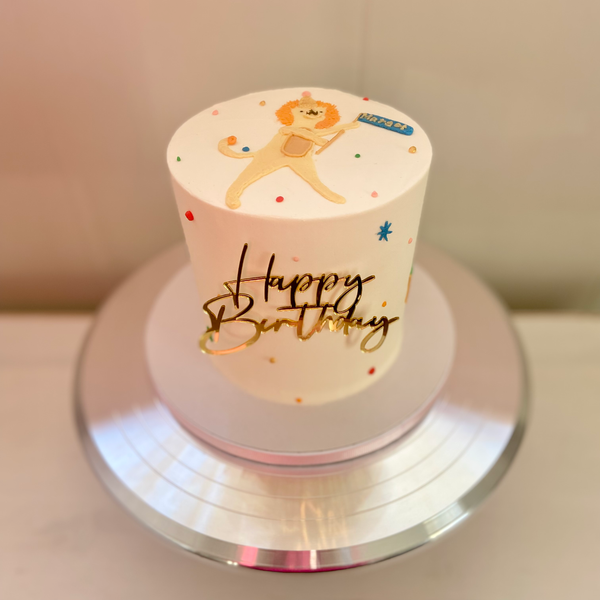 Small birthday cake with a lion design and 'Happy Birthday' text on a stand.