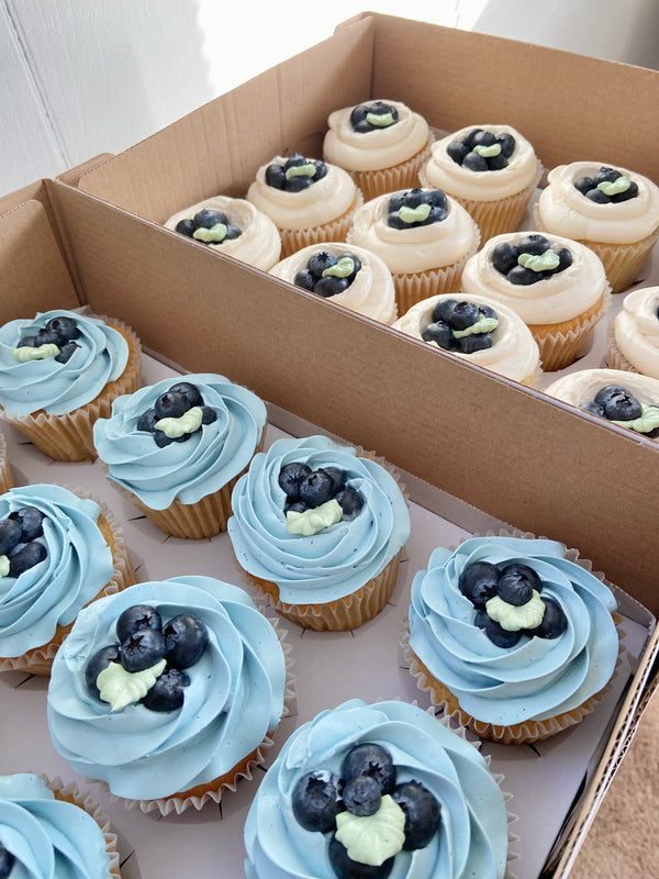 Blue and white cupcakes topped with fresh blueberries.