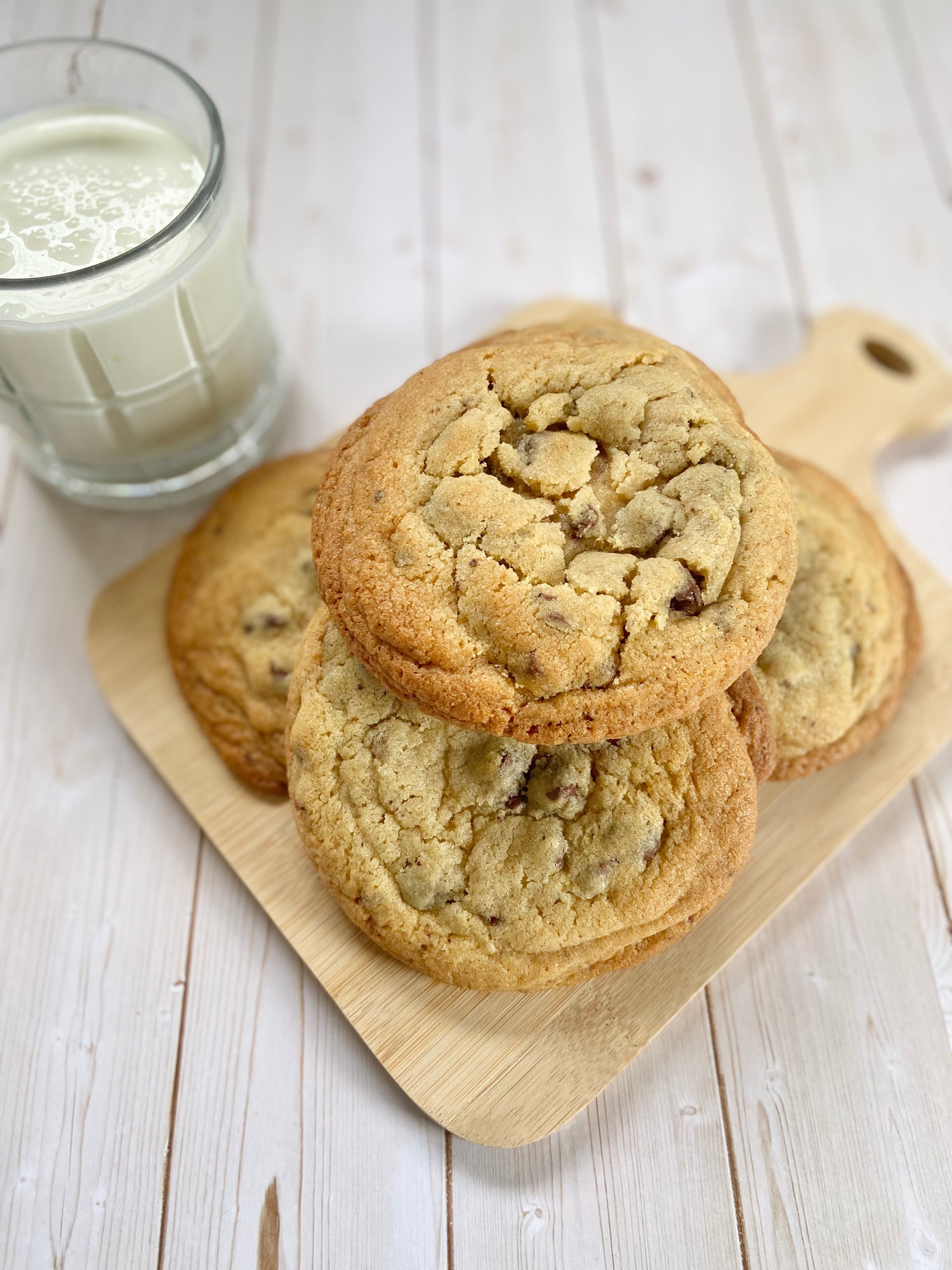Pile of chocolate chip cookies next to a glass of milk.