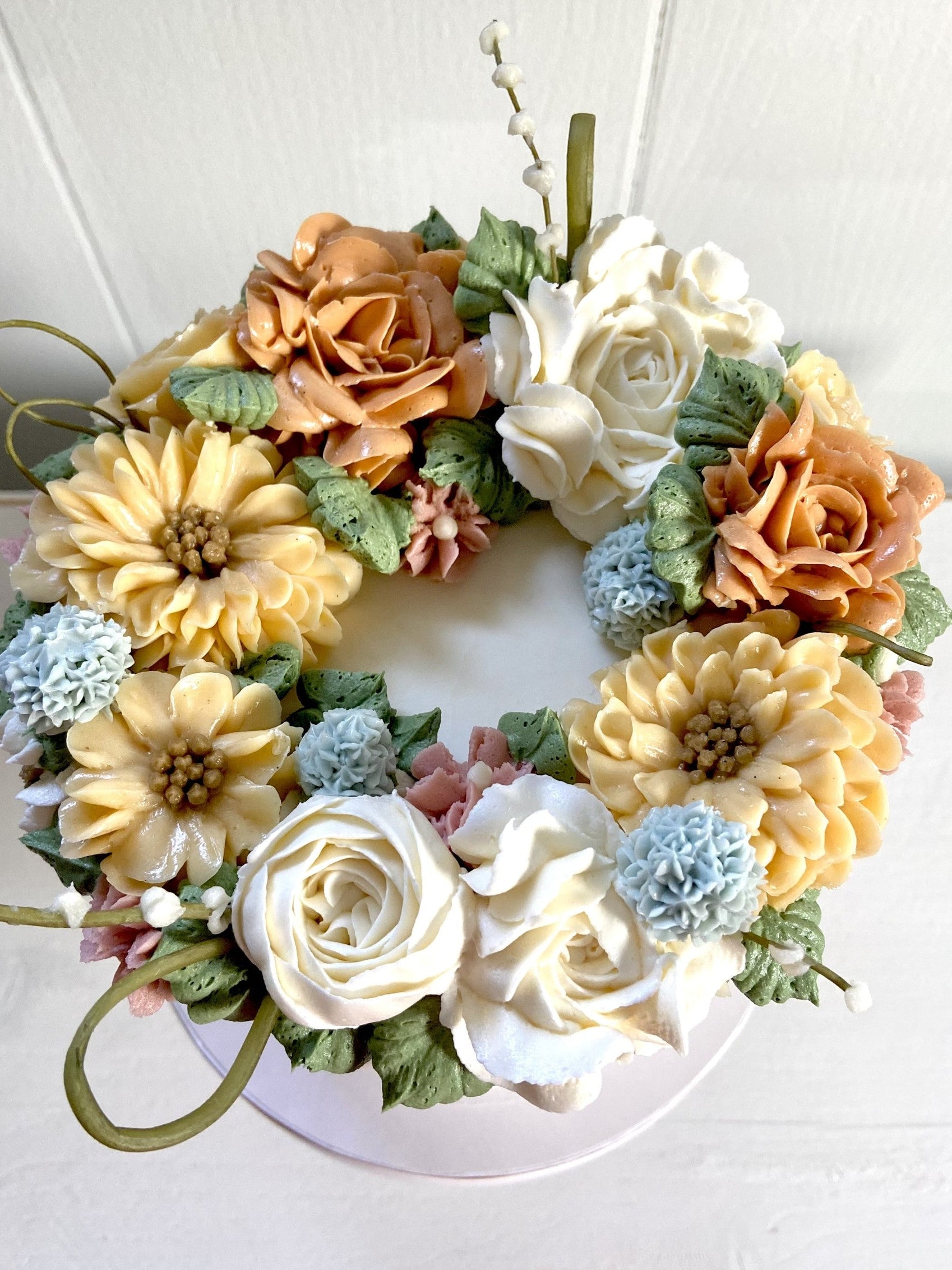 Fall colored buttercream flowers on top of a cake.