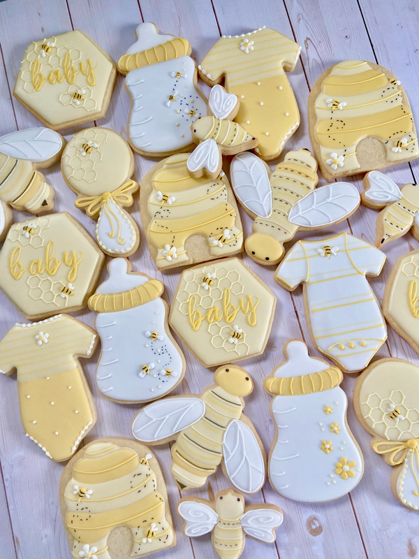 Bee and honey themed decorative cookies shaped like baby items, bees, and beehives. 