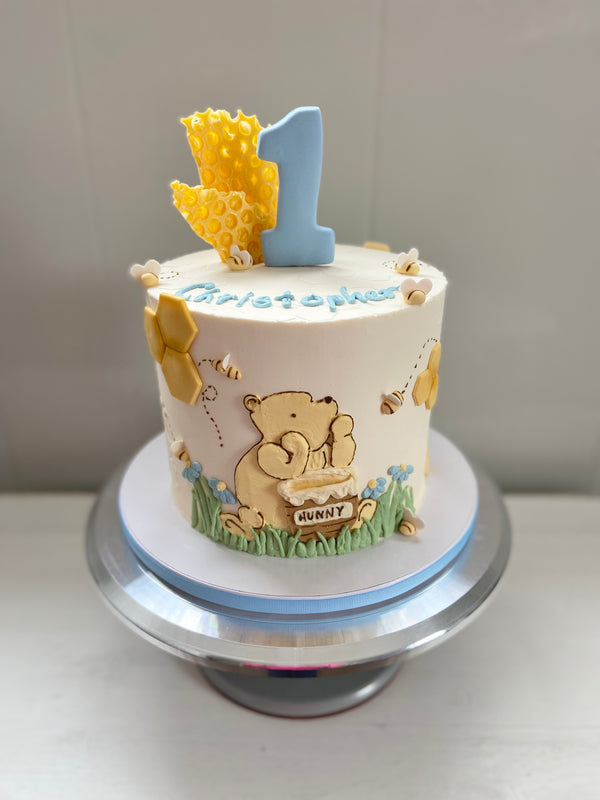 First birthday cake with Winnie the Pooh design on a white background.