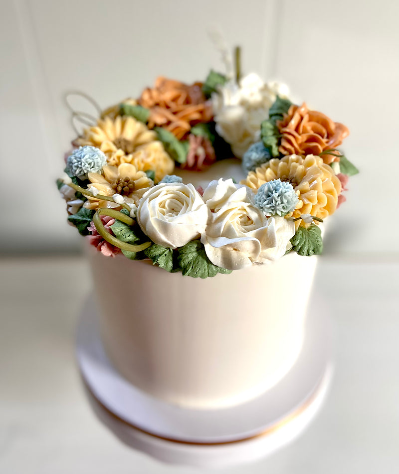 Cake with fall colored buttercream flowers on top.